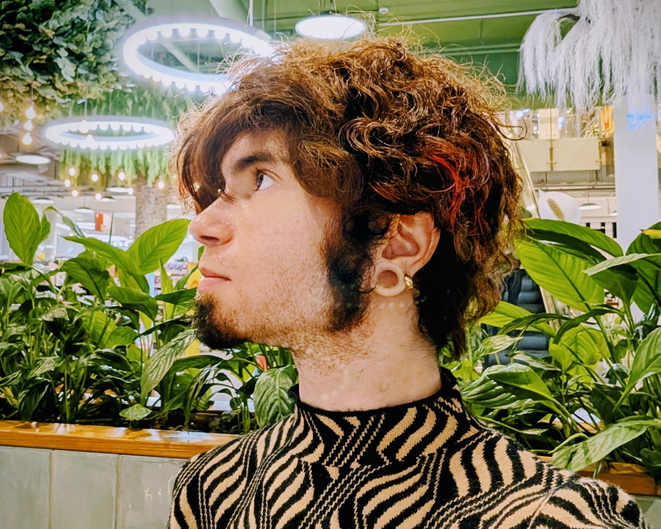 Profile shot in a café showing early facial hair growth on the jaw and chin