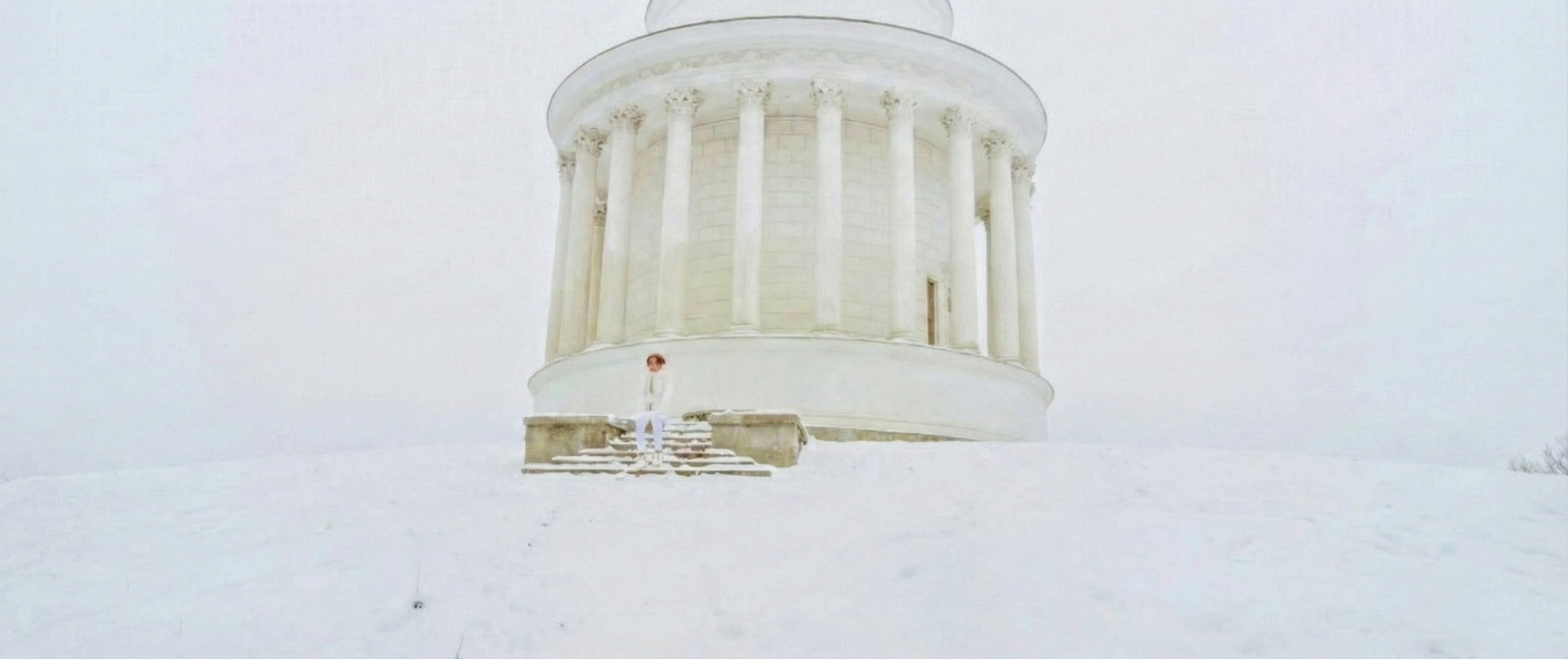 Standing in white on the snow-covered steps of the Temple of Vesta Water Tower in Warsaw during the coldest shoot day