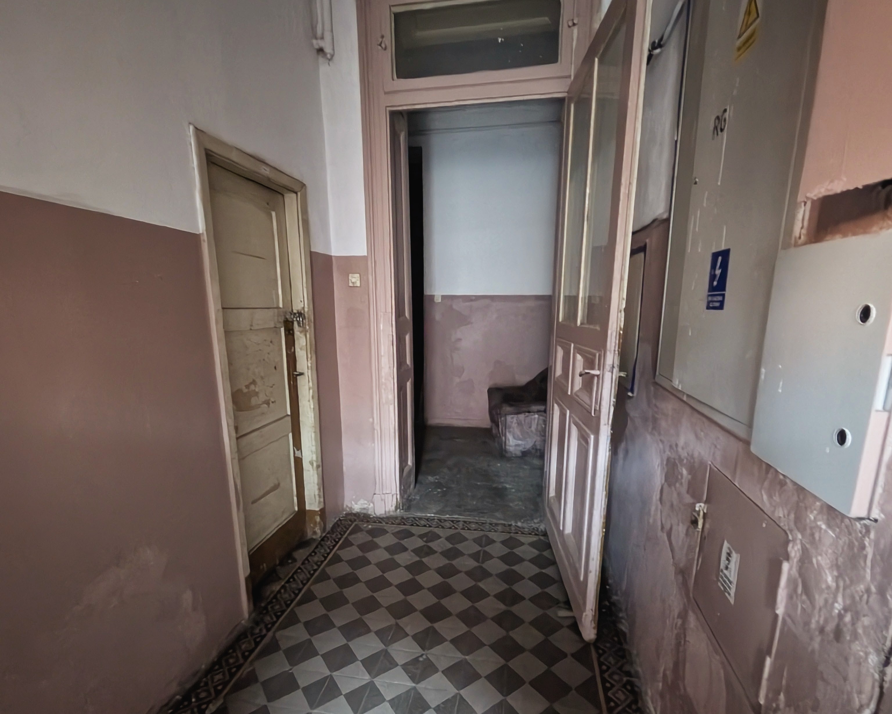 A dim back-alley hallway in Wrocław with peeling walls and a checkered floor, where I waited for the lesson to start